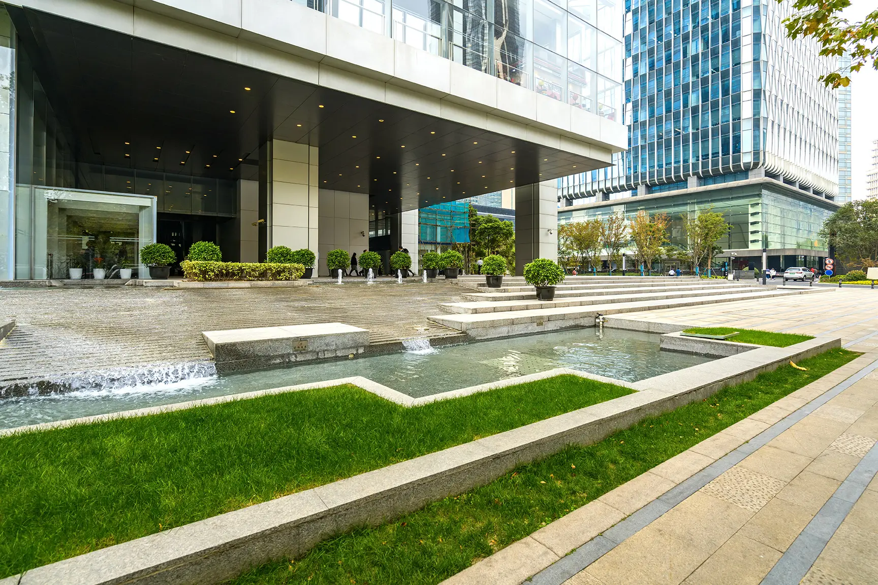 Manicured commercial landscape with water feature outside a modern office building